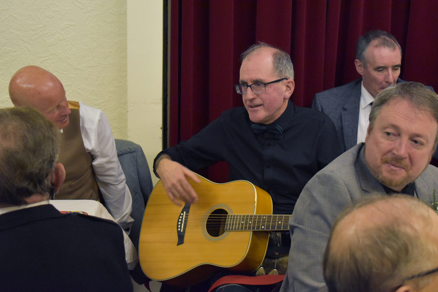 A man plays acoustic guitar among diners