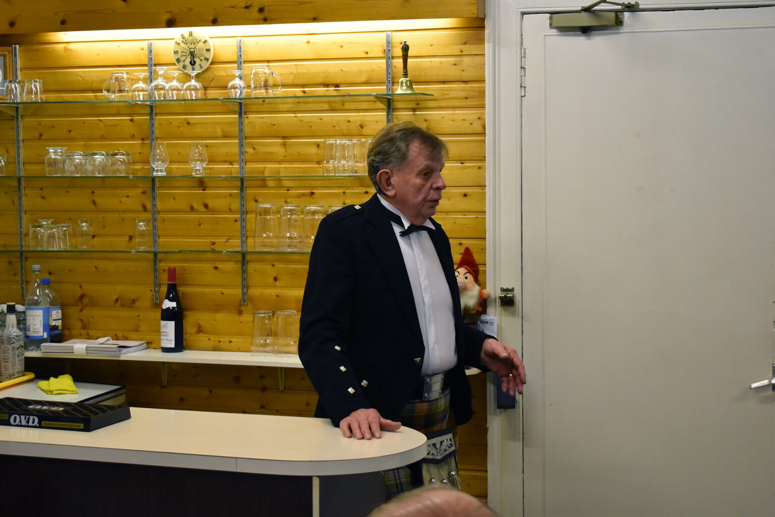 A man in Highland dress sings at the club bar