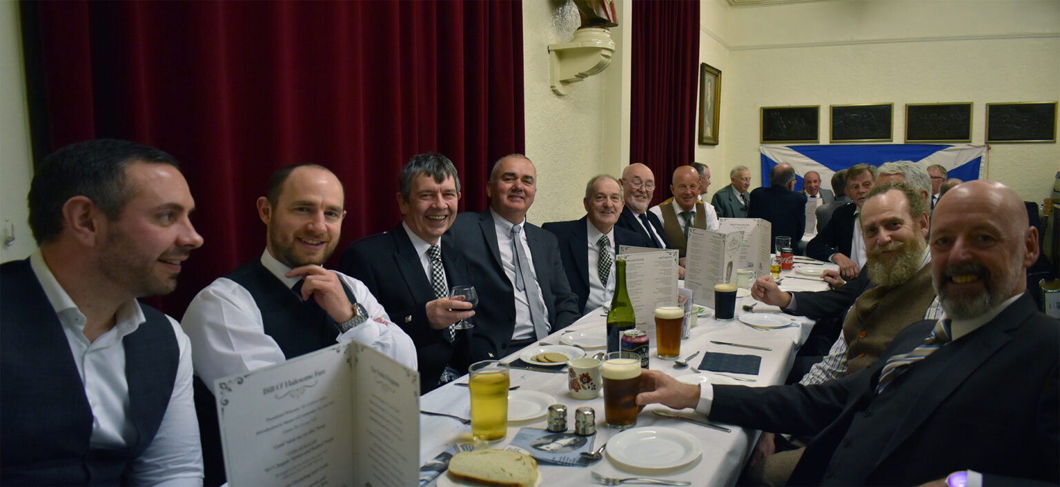 A long table of diners in suits in the club room