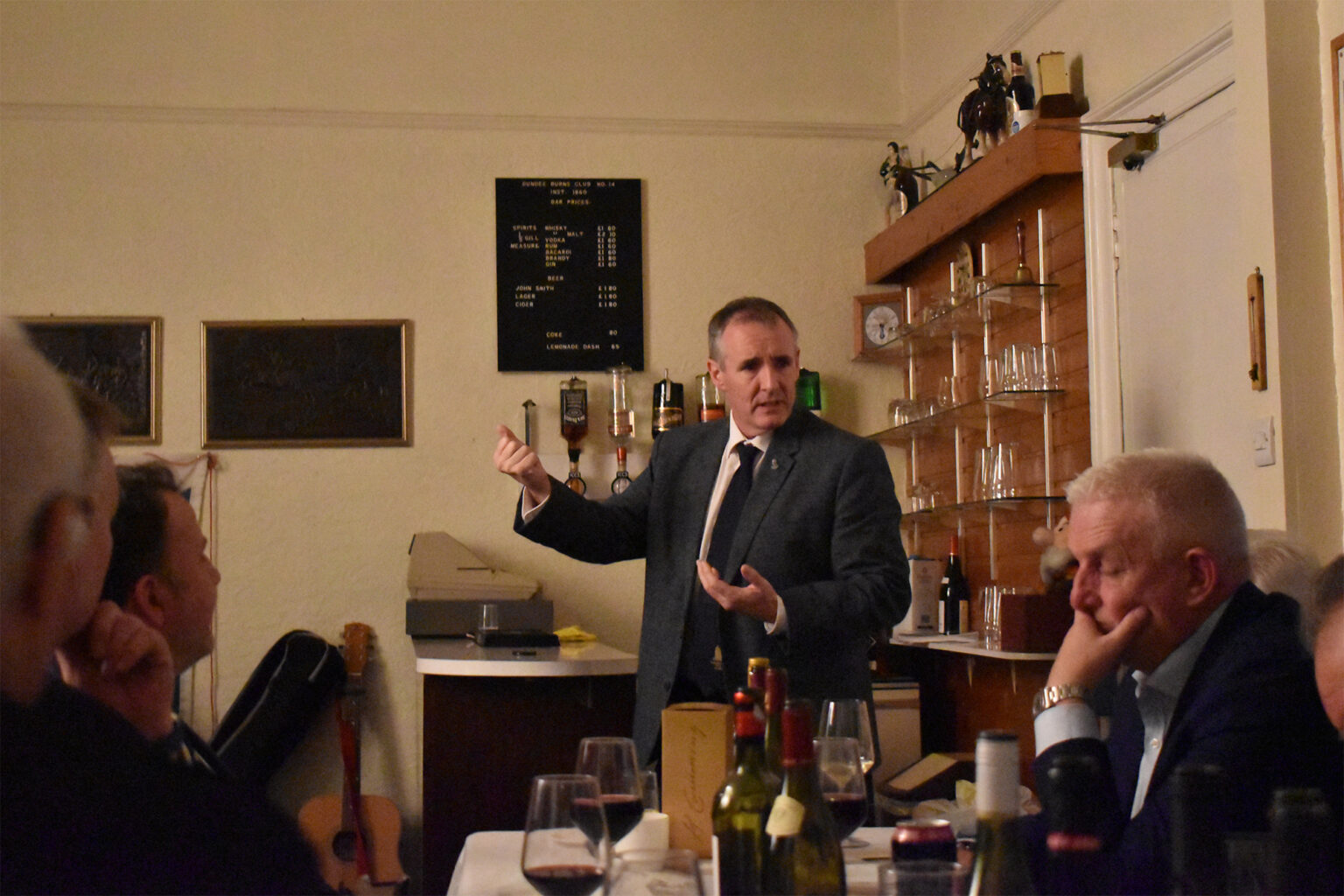 A man recites with arms outstretched in the club room