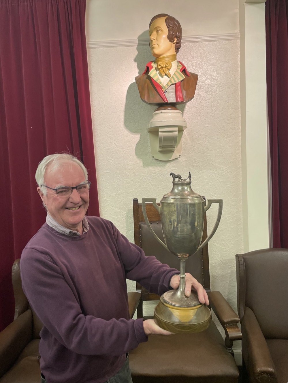 The 1884 Burns Charity Cup, topped by a ploughman and his horse, held up beneath the bust of Burns