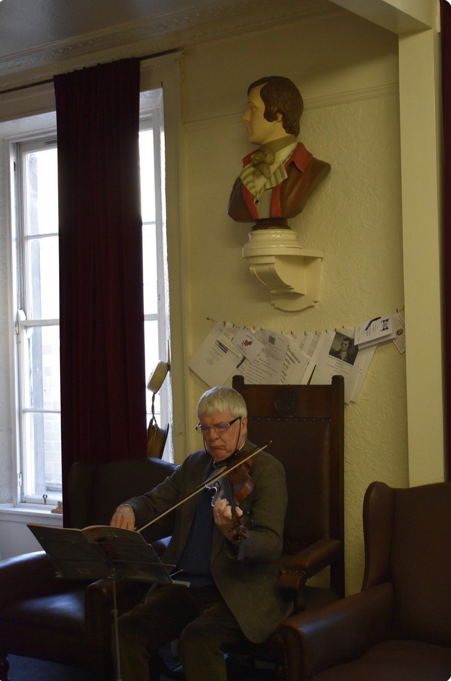 Iain Flett plays Burns on the fiddle beneath the bust of Burns