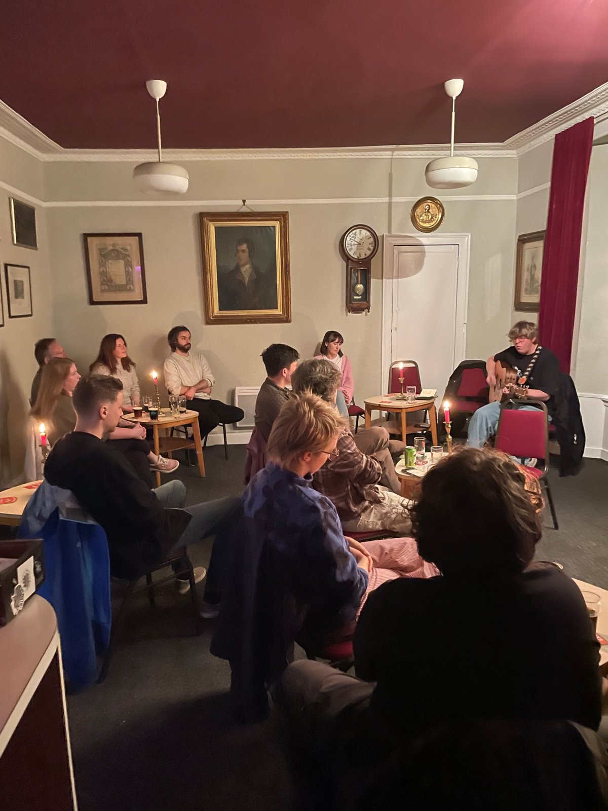 A singer-songwriter evening in the club rooms, beneath a portrait of Burns